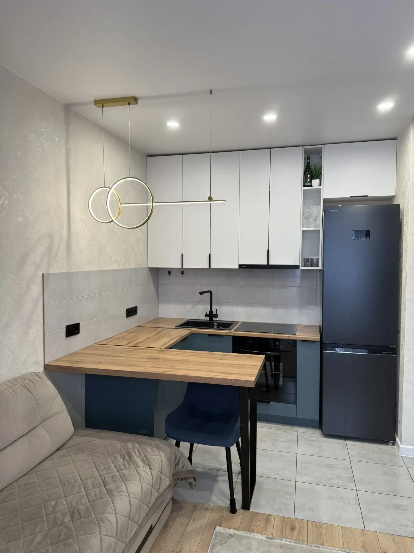 Продаётся уютная евро‑2 в Петровском квартале. Общая площадь — 34,4 квадратных метра.
Новый дизайнерский ремонт. Санузел совместный. Напольные покрытия: в прихожей, ванной и кухонной зоне — кафель, в комнате и гостиной — ламинат. На стенах — обои. Натяжные потолки везде. Точечное освещение в кухонно